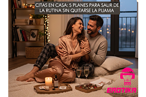 Pareja sonriendo en una cita romántica en casa sobre una alfombra con velas, fresas y copas de champaña.