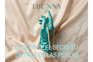 Primer teaser visual: Una mano con guante de satén turquesa sostiene delicadamente un hilo de perlas sobre un fondo de seda champagne y mármol, anunciando el nuevo ritual de bienestar íntimo TBUNNY.