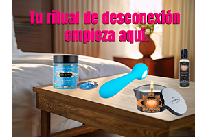 Kit de productos Erotika Love Store sobre mesa de noche: Vela de masaje Ignite, sales de baño Kamasutra, vibrador azul y aceite sensorial en una habitación iluminada.